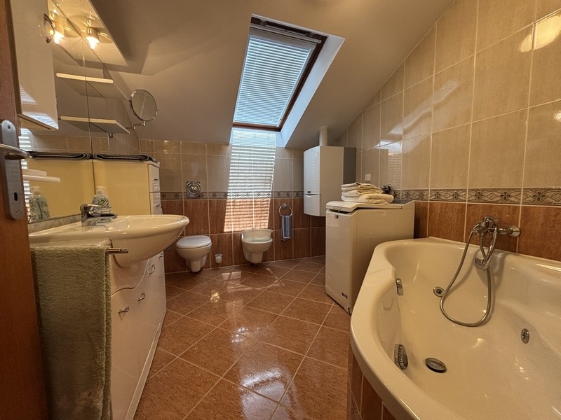 Badezimmer mit Badewanne, Waschmaschine und Dachfenster