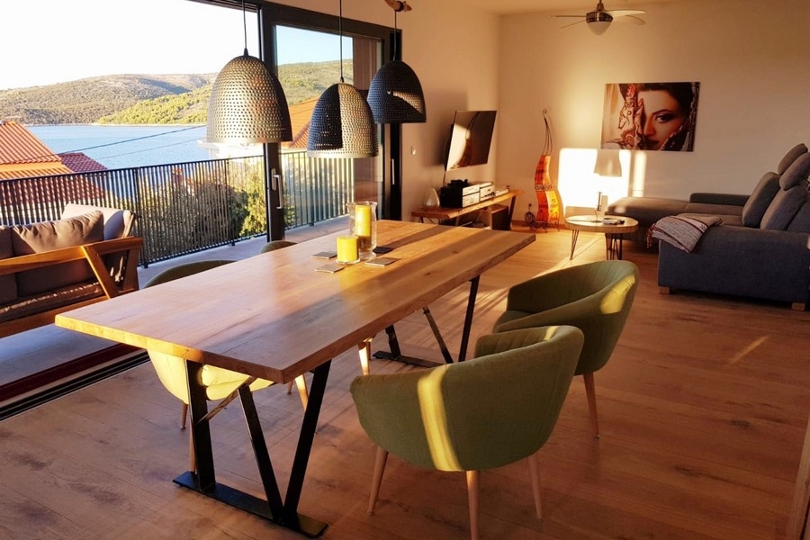 Offener Wohnbereich mit Sofa, Esstisch und Zugang zum Balkon