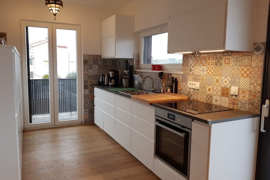 Moderne Küche mit Einbaugeräten und dekorativer Fliesenrückwand