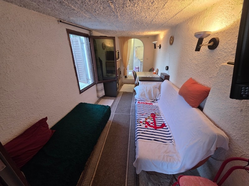 Schmaler Wohnraum mit Sitzgelegenheit und Fenster zur Straßenseite