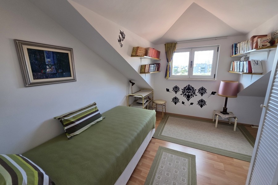 Helles Schlafzimmer im Dachgeschoss mit Einzelbett, Arbeitsbereich und Dachschrägen