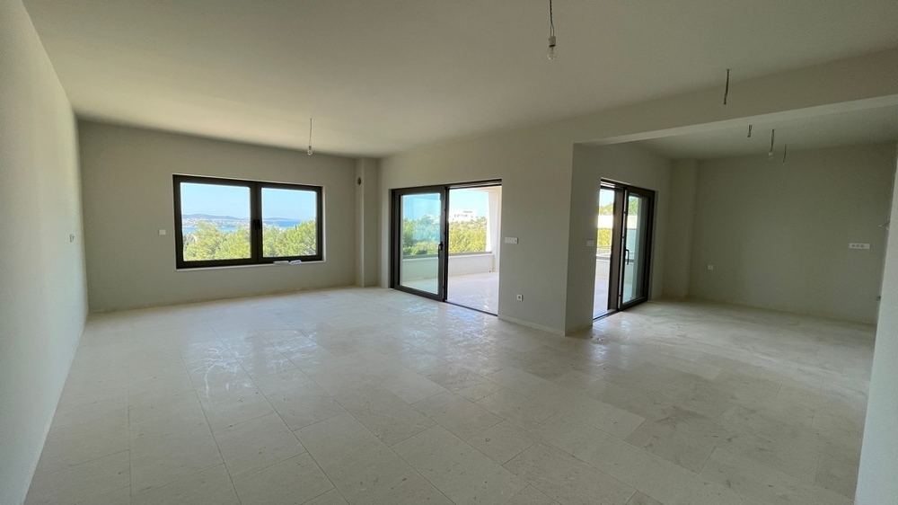 Heller offener Wohnraum mit großen Fensterflächen und Meerblick