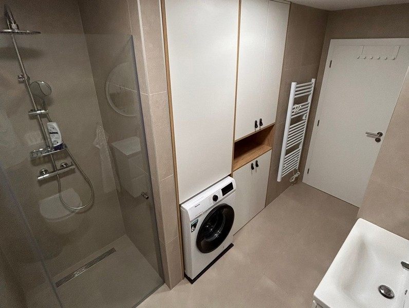 Badezimmer mit Dusche, Waschmaschine und Einbauschrank