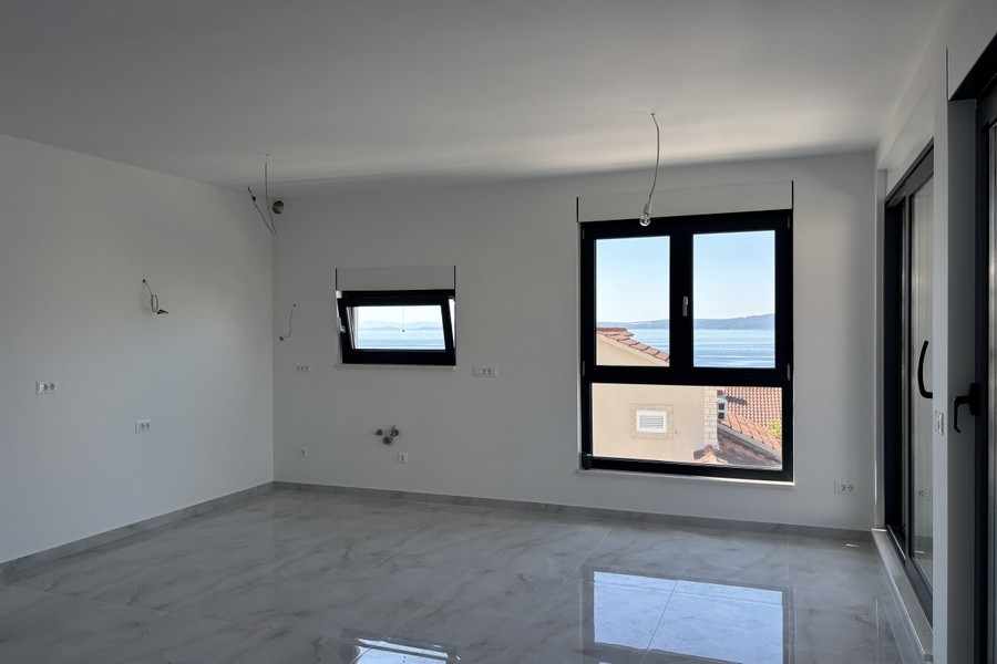 Offener Wohnraum mit Zugang zum Balkon und Blick aufs Meer