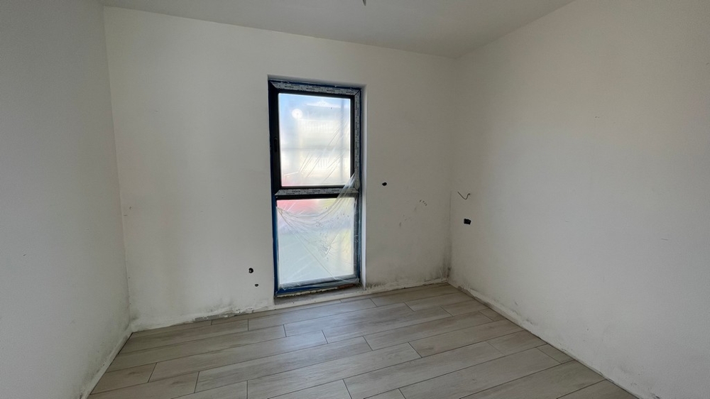 Schlafzimmer mit Fenster und neutraler Ausstattung im Neubau