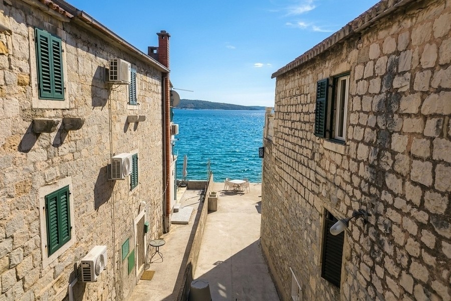 Blick auf das Meer zwischen Natursteinhäusern in Kroatien