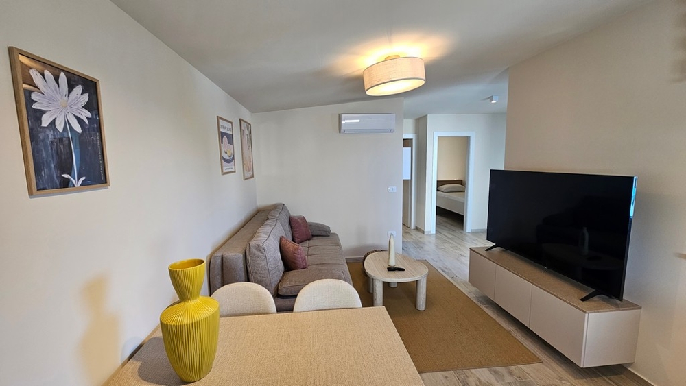 Wohnzimmer mit TV und offenem Küchenbereich