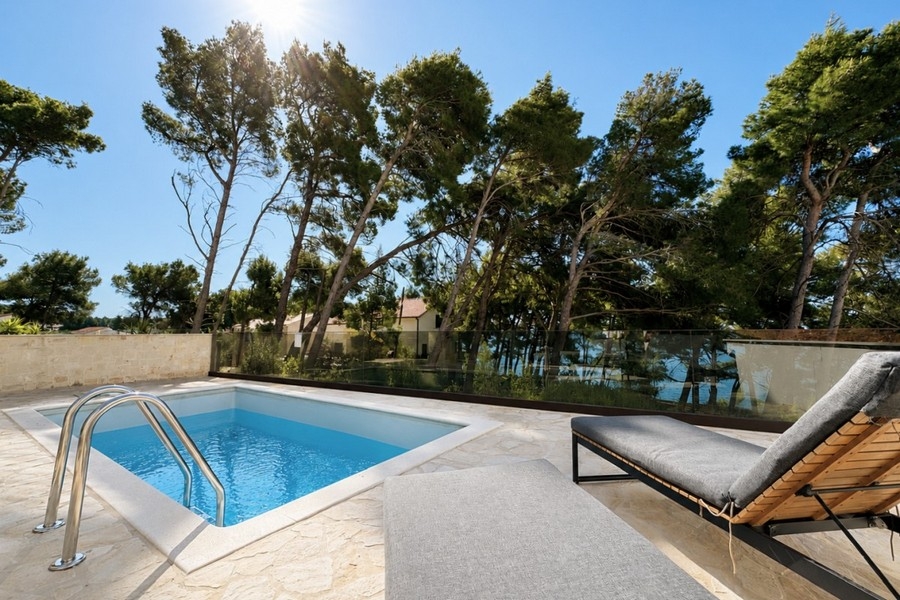 Poolbereich mit Sonnenliegen und Blick auf die Küstenlandschaft