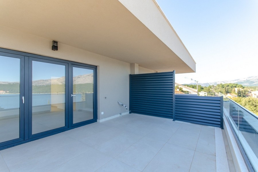 Überdachte Terrasse mit Glasgeländer und Meerblick