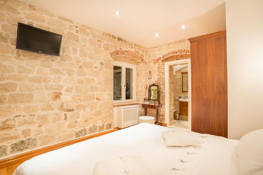 Schlafzimmer mit Natursteinwand und Doppelbett