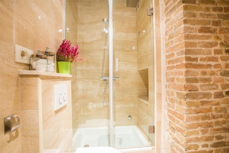 Badezimmer mit Dusche und Natursteinwand
