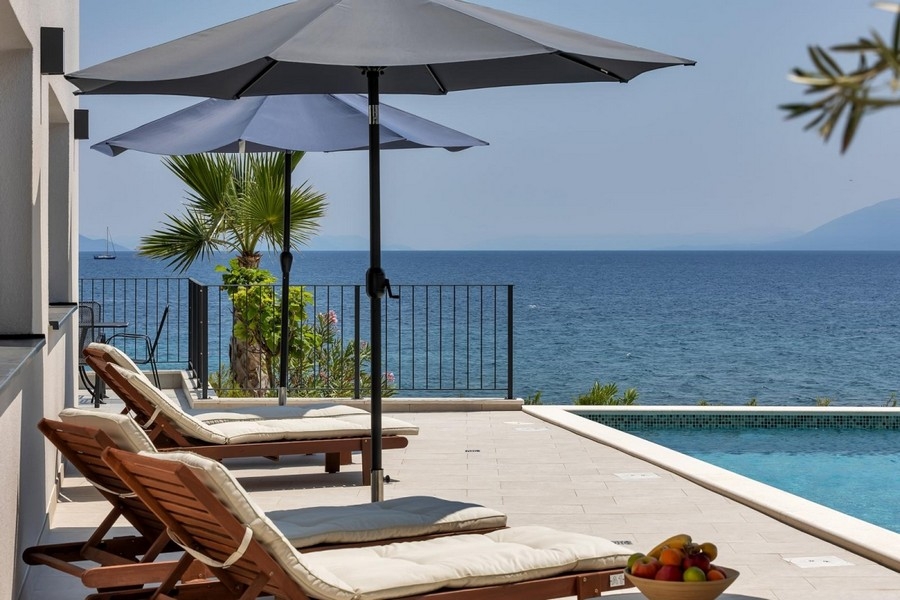 Terrasse mit Sonnenliegen und Meerblick am Pool
