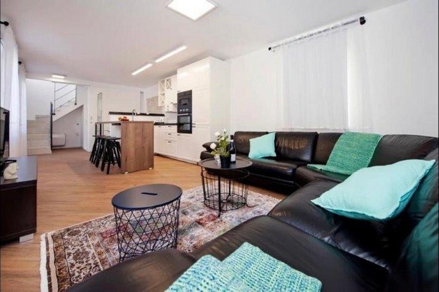 Wohnbereich mit Ledersofa und offener Küche