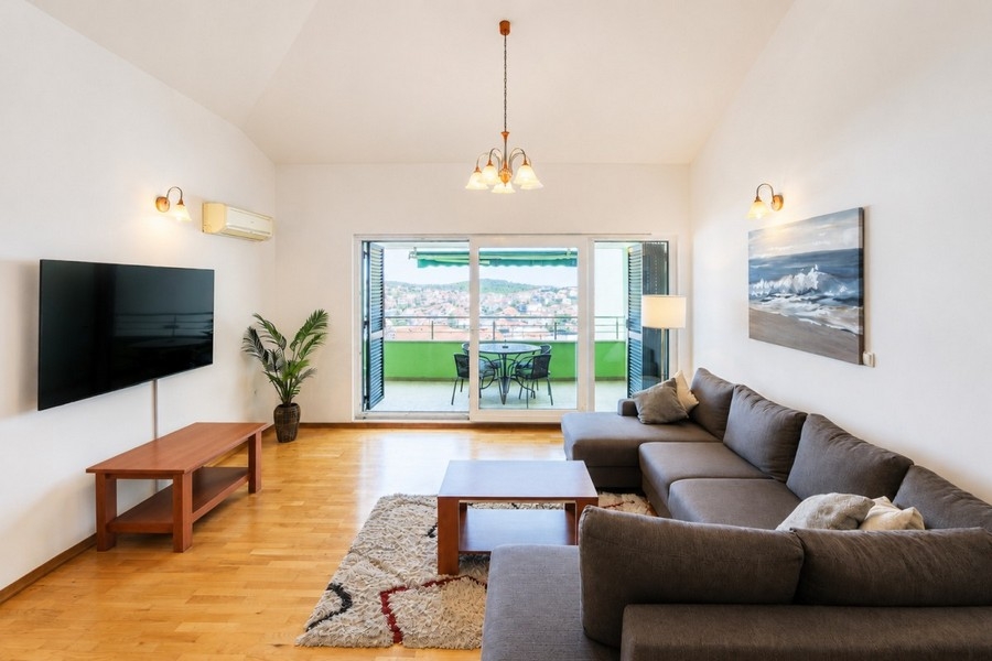 Wohnbereich mit Fernseher und Balkonzugang