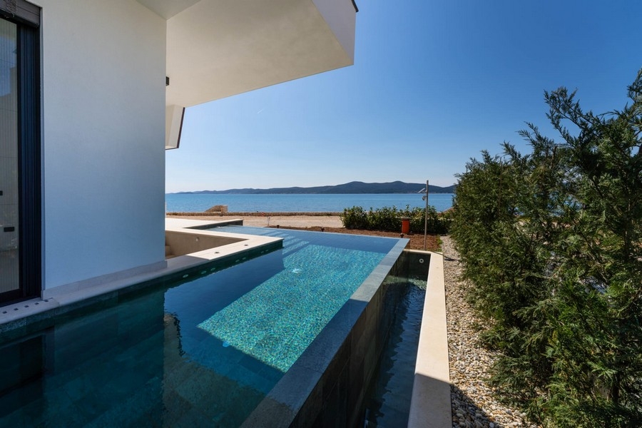 Pool der Wohnung mit Bepflanzung und Meer im Hintergrund
