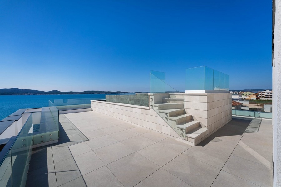 Dachterrasse mit Treppe und Glasgeländer am Meer
