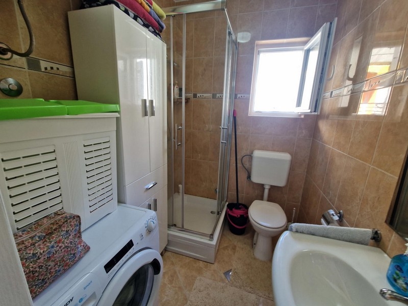Badezimmer mit Duschkabine und Waschmaschine