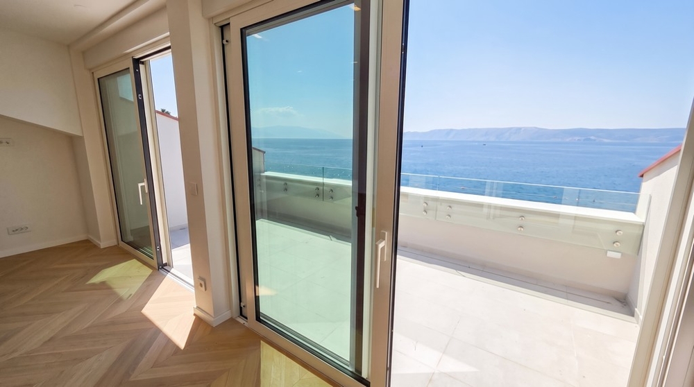 Blick durch die Glastüren auf Terrasse und Meer