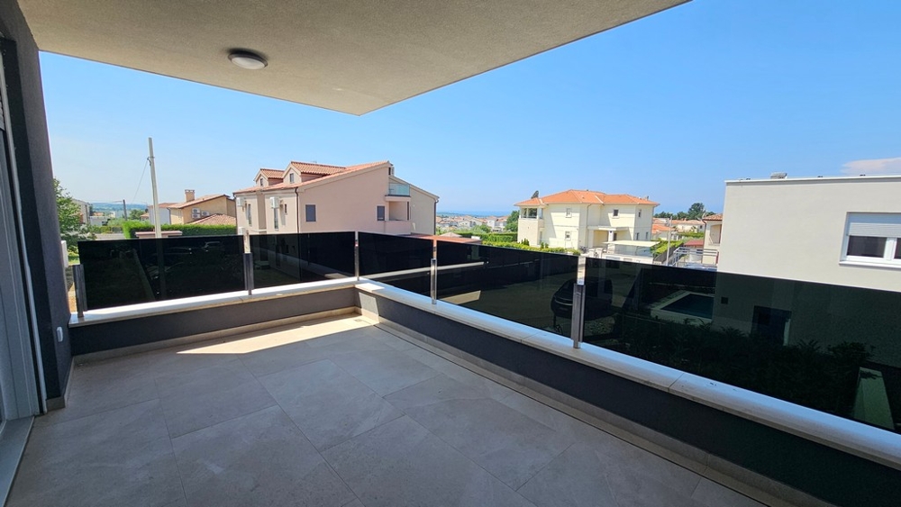 Überdachte Terrasse mit Glasgeländer und Aussicht auf die Umgebung
