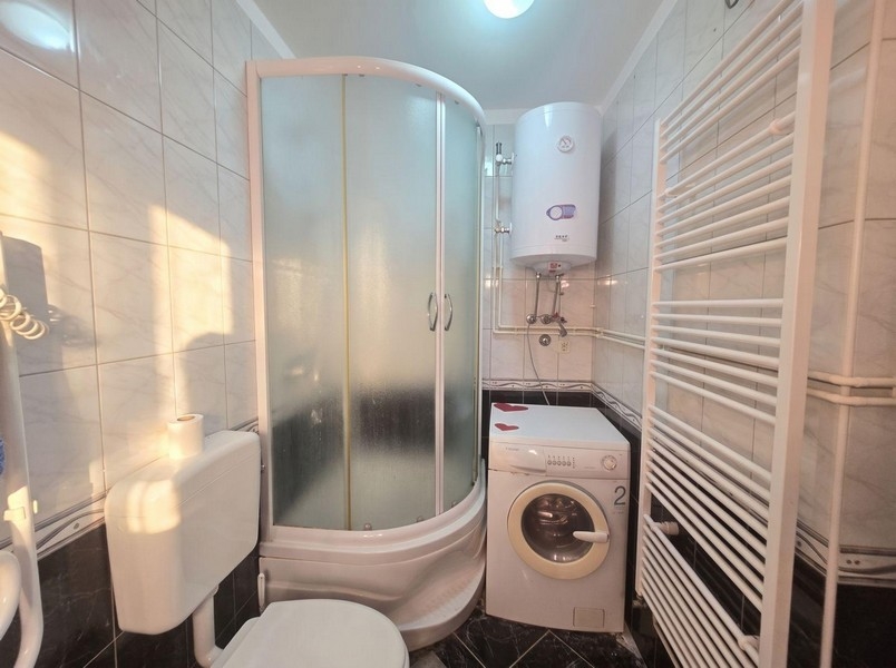 Badezimmer mit Duschkabine und Waschmaschine