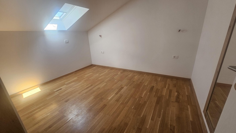 Zimmer mit Dachfenster und Holzboden