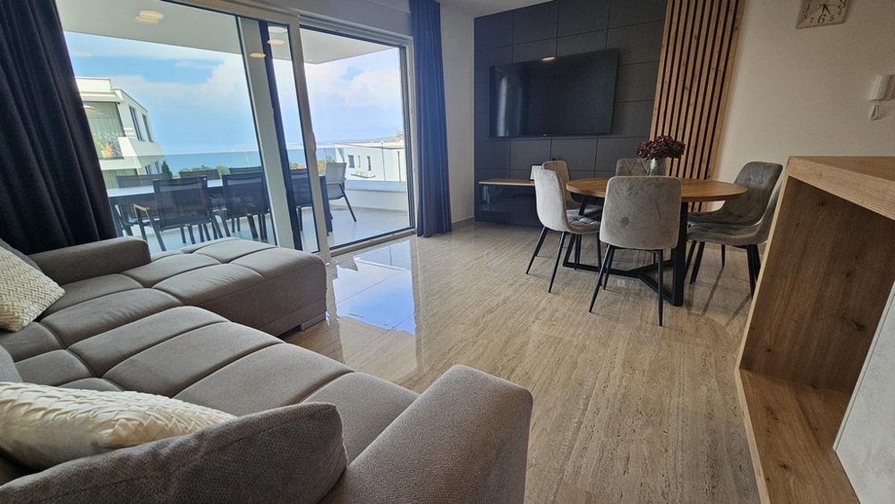 Wohnbereich mit großer Fensterfront und Blick zur Terrasse und zum Meer