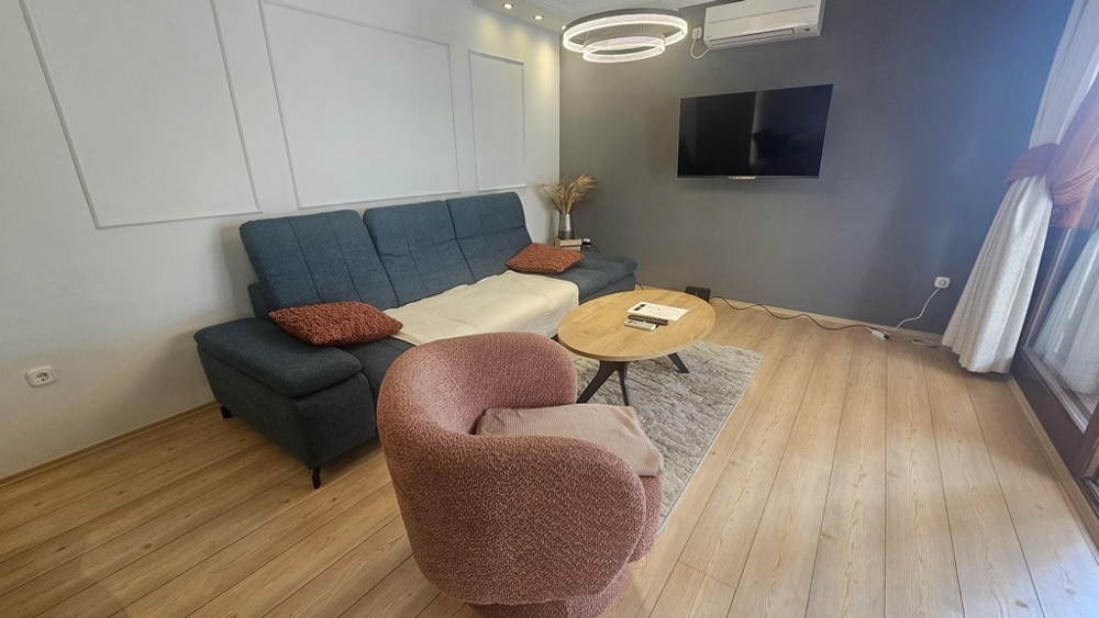Wohnzimmer mit Sofa und Fernseher im renovierten Apartment