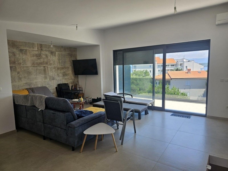 Wohnbereich mit Sofa, Natursteinwand und Zugang zum Balkon