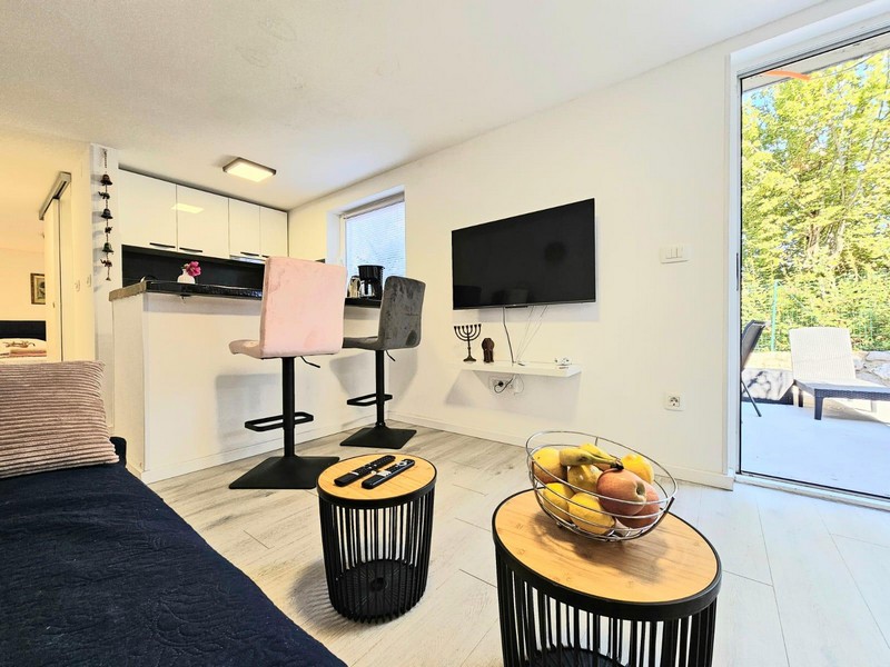 Möblierter Wohnbereich mit Fernseher und Barhockern in Njivice