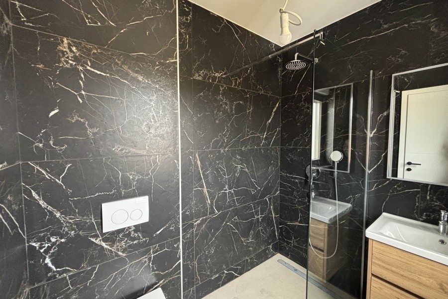 Badezimmer mit dunklen Marmorfliesen und Dusche