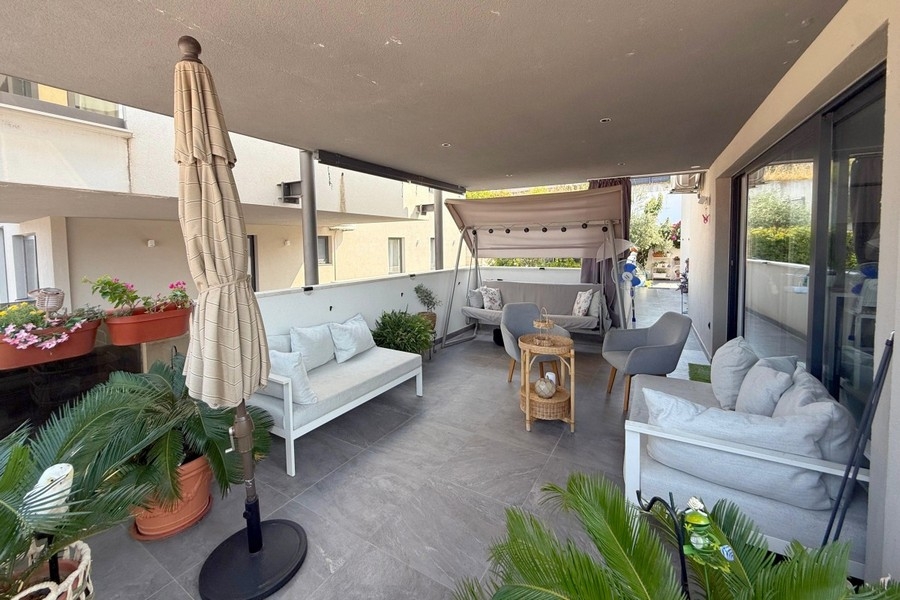 Überdachte Terrasse mit Sitzmöbeln vor dem Wohnbereich