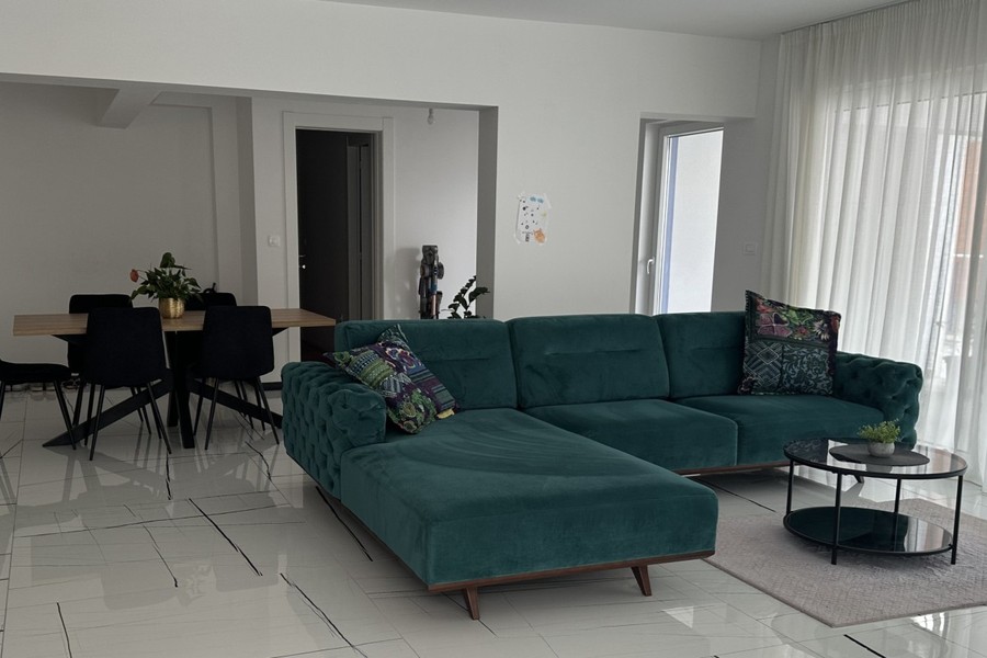 Wohnzimmer mit Ecksofa und großen Fenstern