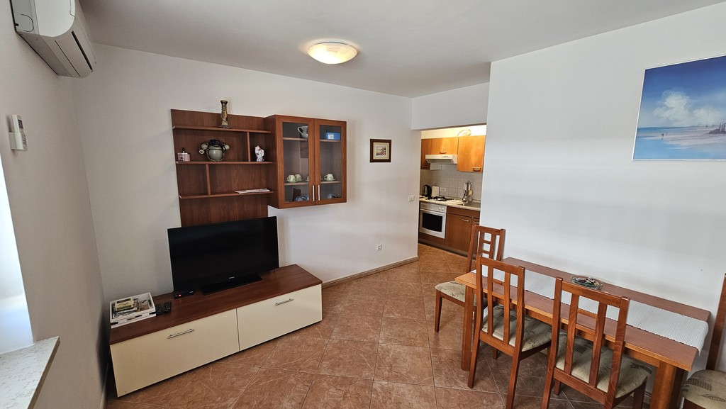 Wohnbereich mit Fernseher, Esstisch und Küche