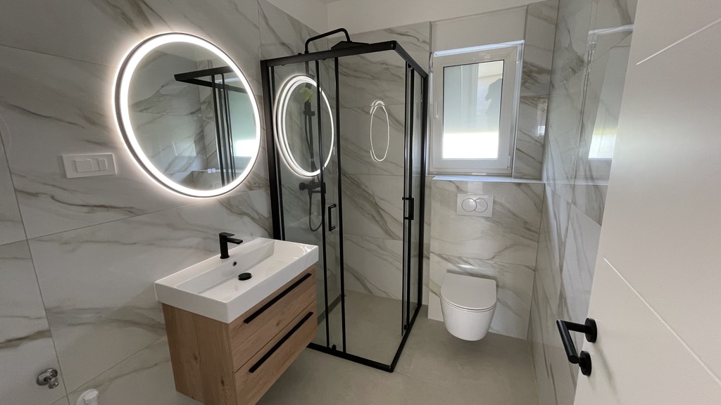 Badezimmer mit Dusche und beleuchtetem Spiegel