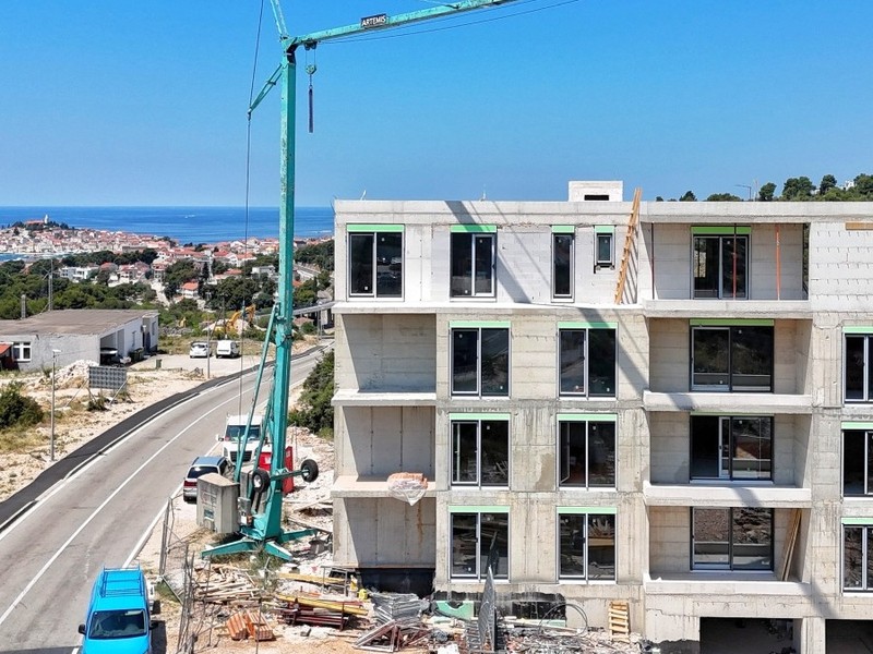 Rohbau mit Kran, dahinter die Altstadt am Meer