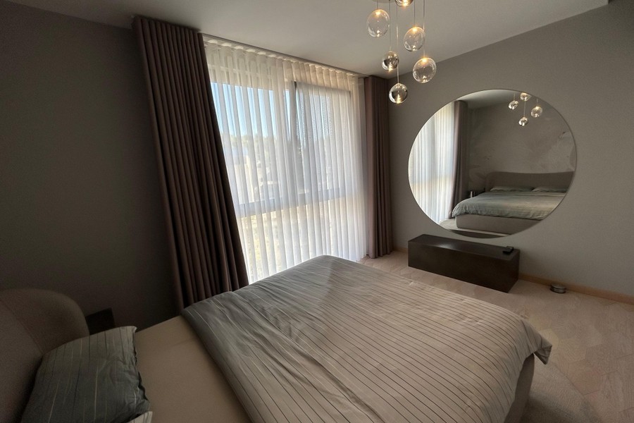 Schlafzimmer mit Wandspiegel und Vorhängen