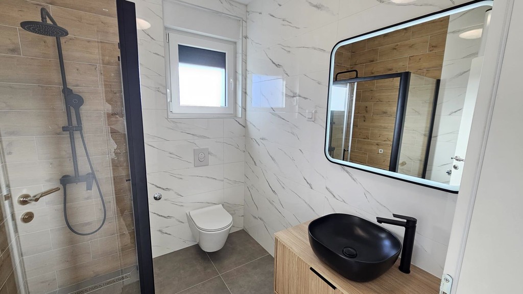 Badezimmer mit Dusche und Wandspiegel