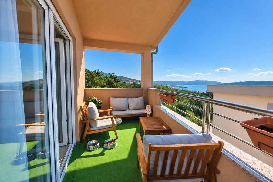 Balkon mit Holzmöbeln und Blick auf das Meer