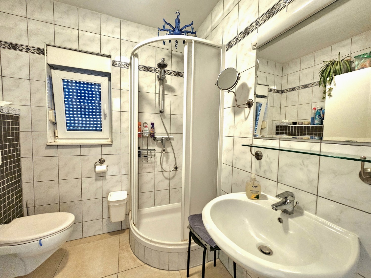 Badezimmer mit Eckdusche, Waschbecken und Toilette
