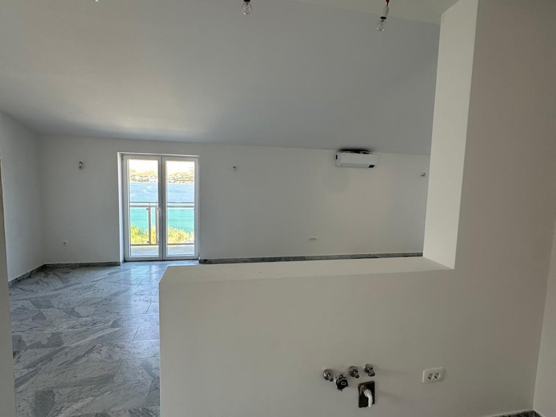 Wohnzimmer mit offenem Küchenbereich und Fenster zum Meer