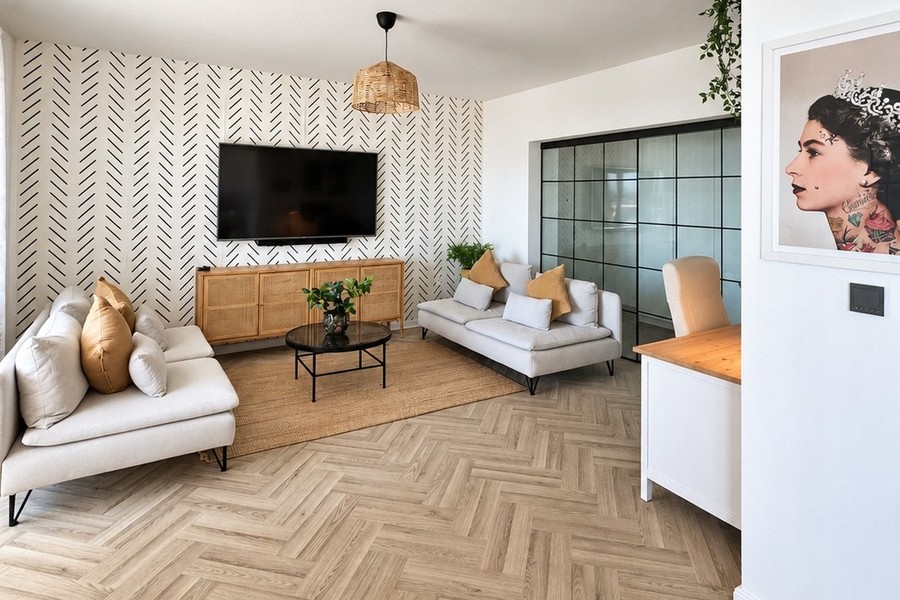 Wohnzimmer mit Sofa, Fernseher und Fischgrätparkett