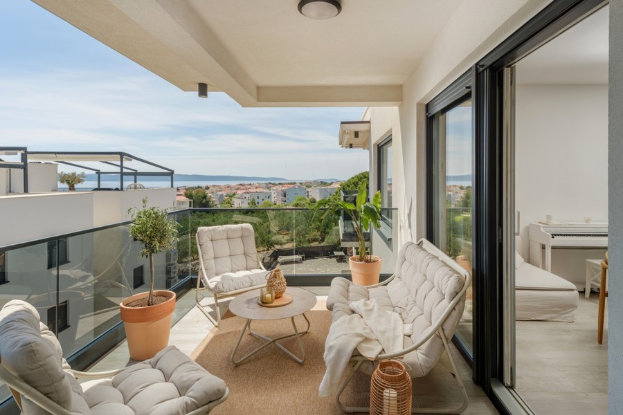 Überdachte Terrasse mit Sesseln und Blick zum Meer